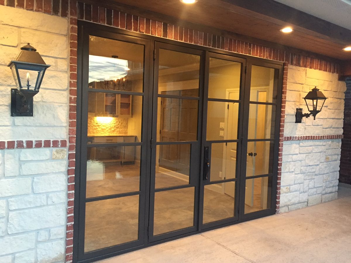 Steel accordion glass doors on brick structure at dusk