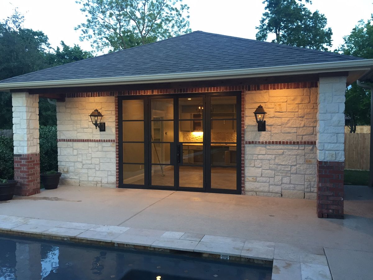 Exterior stone facade with large glass doors and lighting
